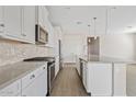Bright kitchen features white cabinetry, stainless steel appliances, stone backsplash and an oversized island at 25424 S 224Th Pl, Queen Creek, AZ 85142