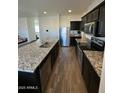 Bright kitchen with stainless steel appliances, granite counters, and dark cabinets at 36992 W Capri Ave, Maricopa, AZ 85138