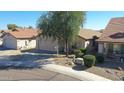 Street view of a single-story house with mature trees and a well-kept front yard at 2411 W Oberlin Way, Phoenix, AZ 85085