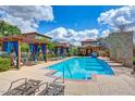 Community pool with blue water, lounge chairs, pergola, and nearby buildings at 4710 E Tierra Buena Ln, Phoenix, AZ 85032