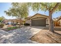 Expansive driveway leading to a home with a two-car garage, complemented by mature landscaping at 9331 W Harmony Ln, Peoria, AZ 85382