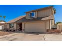 Tan two story home with front yard, two car garage, red brick detail, and blue skies at 1027 W Natal Ave, Mesa, AZ 85210