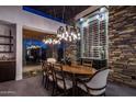 Elegant dining room with a wine storage, a large table, and modern chandelier lighting at 10381 E Loving Tree Ln, Scottsdale, AZ 85262