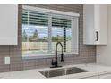 Kitchen sink featuring modern faucet, gray backsplash, and open view to the pool at 12444 N 33Rd St, Phoenix, AZ 85032