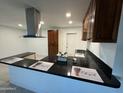 Modern kitchen with black countertops, stainless steel hood and dark-wood cabinets at 2301 W Montebello Ave, Phoenix, AZ 85015