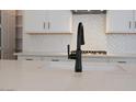 Close-up of the modern kitchen island featuring a sleek black faucet and a quartz countertop with stylish backsplash at 40113 N Alameda Dr, San Tan Valley, AZ 85140