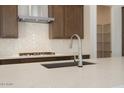 Close-up of the kitchen island with a modern faucet, quartz countertops, and a stylish backsplash at 40129 N Alameda Dr, San Tan Valley, AZ 85140