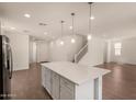 Bright kitchen with an island perfect for entertaining, flowing into an open floor plan with staircase and wood tile floors at 11623 W Green Dr, Youngtown, AZ 85363
