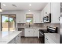 Well-lit kitchen boasts stainless steel appliances, quartz countertops, and sleek white cabinets at 11627 W Green Dr, Youngtown, AZ 85363