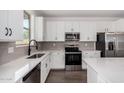 Modern kitchen features white cabinetry, stainless steel appliances, and quartz countertops at 11627 W Green Dr, Youngtown, AZ 85363