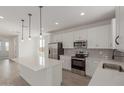 Well-lit kitchen with stainless steel appliances, white cabinetry, and a quartz-topped island at 11631 W Green Dr, Youngtown, AZ 85363