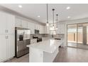 Bright kitchen featuring white cabinetry, stainless steel appliances, a large island, and sliding glass doors to the backyard at 11631 W Green Dr, Youngtown, AZ 85363