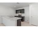 Modern kitchen featuring sleek black cabinetry, stainless steel appliances, and a stylish breakfast bar with marble countertops at 35474 N Breezy Ln, San Tan Valley, AZ 85140