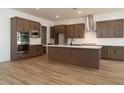 Modern kitchen with stainless steel appliances, a large island, and wood look ceramic tile flooring at 40165 N Alameda Dr, San Tan Valley, AZ 85140