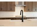 Close-up of the kitchen island featuring white counters, stylish faucet, and stainless steel appliances at 40165 N Alameda Dr, San Tan Valley, AZ 85140