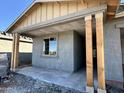 Unfinished front porch area, showcasing the natural wood pillars and textured exterior coating waiting for paint at 5629 W Mcneil St, Laveen, AZ 85339