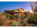 Desert landscaping surrounds the entrance of this southwestern-style home with stone and stucco exterior at 7413 E Lower Wash Pass, Scottsdale, AZ 85266