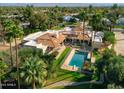 Aerial view of large home with swimming pool, tile roof, mature landscaping and palm trees at 8712 N 64Th Pl, Paradise Valley, AZ 85253