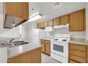 Well-lit kitchen featuring matching wood cabinets, white appliances, and laminate countertops at 12123 W Bell Rd # 241, Surprise, AZ 85378