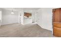 Open-concept living area with wood-look floors flowing into dining space and access to the bathroom at 12123 W Bell Rd # 241, Surprise, AZ 85378