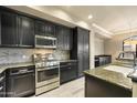 Kitchen with granite countertops, stainless steel appliances, black cabinetry, and tile backsplash at 7601 E Indian Bend Rd # 2056, Scottsdale, AZ 85250