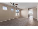 Spacious living room featuring carpeted floors, a ceiling fan, and multiple windows at 10287 S 175Th Ave, Goodyear, AZ 85338