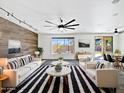 Bright living room with modern decor, a wood accent wall, and large windows providing natural light at 1227 E Indigo St, Gilbert, AZ 85298