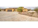 Tan home with an expansive driveway leading to multiple garages on a large desert lot at 8210 S 132Nd Ave, Goodyear, AZ 85338