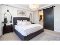 A spacious primary bedroom features a gray tufted headboard, barn door entrance to the en-suite bath and a lovely area rug at 20906 E Macaw Dr, Queen Creek, AZ 85142