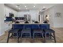 A modern kitchen featuring stainless steel appliances, white cabinets, a blue island, and bar stool seating at 2544 W Pumpkin Ridge Dr, Anthem, AZ 85086