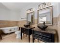Bathroom featuring dual vessel sinks with dark cabinets, a clawfoot tub, and tiled walls at 3397 E Derringer Way, Gilbert, AZ 85297