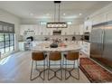 Modern white kitchen with large island, stainless steel appliances, and bar seating area at 3811 N 64Th St, Scottsdale, AZ 85251