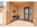 Inviting covered front porch with tiled flooring, seating, decorative wall art and glass door at 4086 E Narrowleaf Dr, Gilbert, AZ 85298