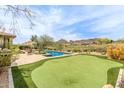 Scenic backyard with lush landscaping, pool, putting green, and mountain views at 9440 N Sunset Rdg, Fountain Hills, AZ 85268