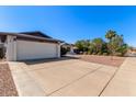 Exterior of lovely single-story home with a spacious driveway, desert landscaping, and mature trees at 1311 W Palo Verde Dr, Chandler, AZ 85224