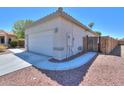 Image showcases a side view of the house highlighting the 2 car garage, side gate and low maintenance landscaping at 1825 E Sycamore Rd, Casa Grande, AZ 85122