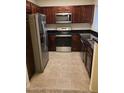 Galley style kitchen with dark wood cabinets, stainless appliances, granite countertops and tile flooring at 5335 E Shea Blvd # 1035, Scottsdale, AZ 85254