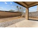 Private backyard with an extended patio, desert landscaping and a block fence at 701 Dylan Ct, Wickenburg, AZ 85390