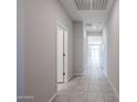 Bright hallway featuring tile flooring, neutral paint, and white doors leading to various rooms at 35295 W La Paz St, Maricopa, AZ 85138