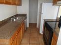 Functional kitchen featuring wood cabinets, double sink, tile flooring, and essential appliances for convenient meal preparation at 5221 N 42Nd Ln, Phoenix, AZ 85019