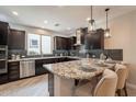 Stylish kitchen featuring dark wood cabinets, granite countertops, stainless steel appliances, and barstool seating at 631 E Peach Tree St, Queen Creek, AZ 85140