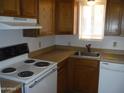 Bright kitchen featuring wood cabinets, laminate countertops, and white appliances including a dishwasher at 8371 W Santa Cruz Blvd, Arizona City, AZ 85123