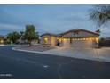 Dusk view of a single-story home with a three-car garage and desert landscaping at 9821 E Glencove St, Mesa, AZ 85207