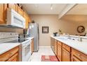 Functional kitchen featuring wood cabinets, white appliances, and tile flooring at 1951 N 64Th St # 26, Mesa, AZ 85205