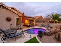 Inviting backyard pool featuring a rock waterfall, lounge chairs, covered patio, and lush landscaping at 23175 W Arrow Dr, Buckeye, AZ 85326