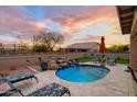 Inviting backyard oasis featuring a custom pool, travertine patio, and seating, perfect for relaxing and entertaining at 23175 W Arrow Dr, Buckeye, AZ 85326