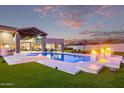 Exterior view of backyard pool with fire features, green lawn, and luxurious seating at 29501 N 76Th St, Scottsdale, AZ 85266