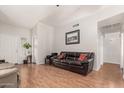 A bright living room featuring wood floors, high ceilings, and a dark leather sofa with red pillows at 7410 W Eva St, Peoria, AZ 85345