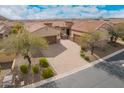 Aerial view of the home's exterior features a brick driveway and desert landscaping under a bright sky at 9041 E Ivyglen Cir, Mesa, AZ 85207