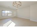 Bright, open-concept living space with neutral tile flooring and contemporary lighting fixture at 9939 W Southgate Ave, Tolleson, AZ 85353